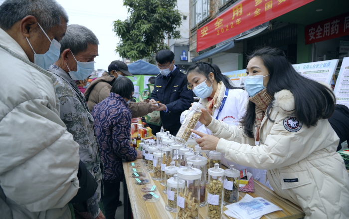 图为工作人员现场向群众讲解常用中药材的鉴别知识，普及药品安全相关法律法规。